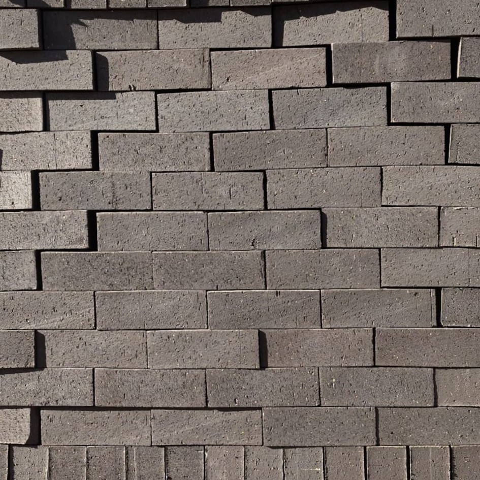 Black Brick Travertine Face Brick featuring a deep black color and a rugged, pitted stone-like texture for modern masonry.