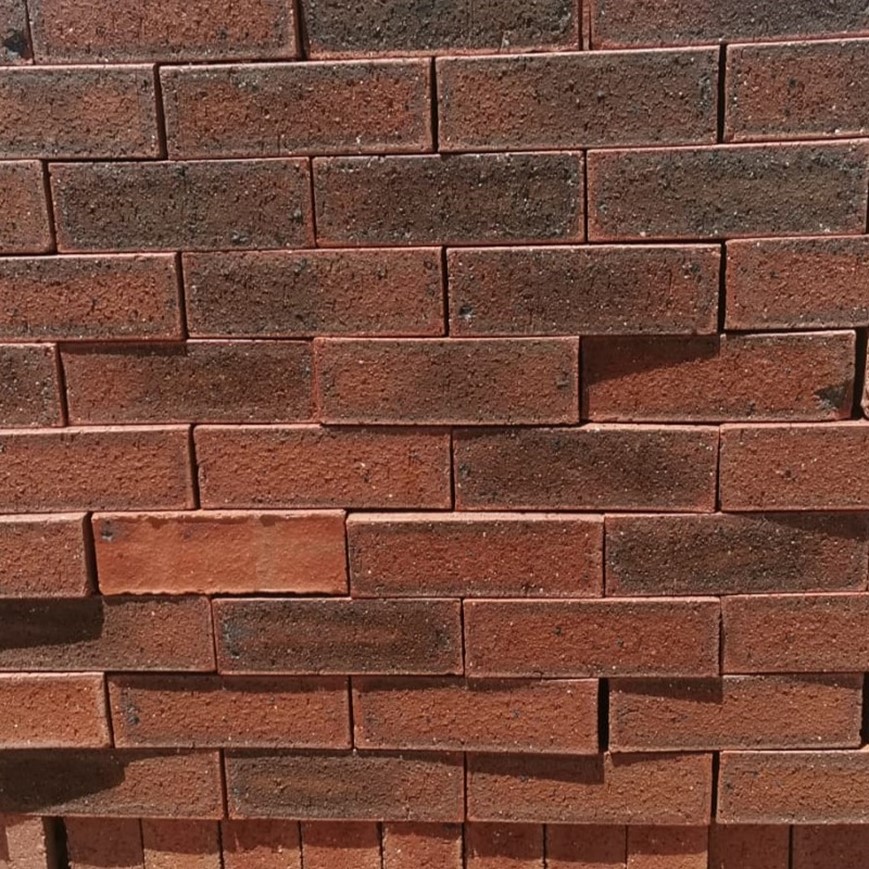 Blackwood Travertine Face Brick featuring a deep dark red color palette and a rugged, pitted stone-like texture.