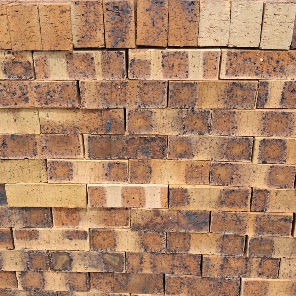 Iroko Travertine Face Brick featuring a blend of peach and dark dappled tones with a rugged travertine finish for characterful building facades.