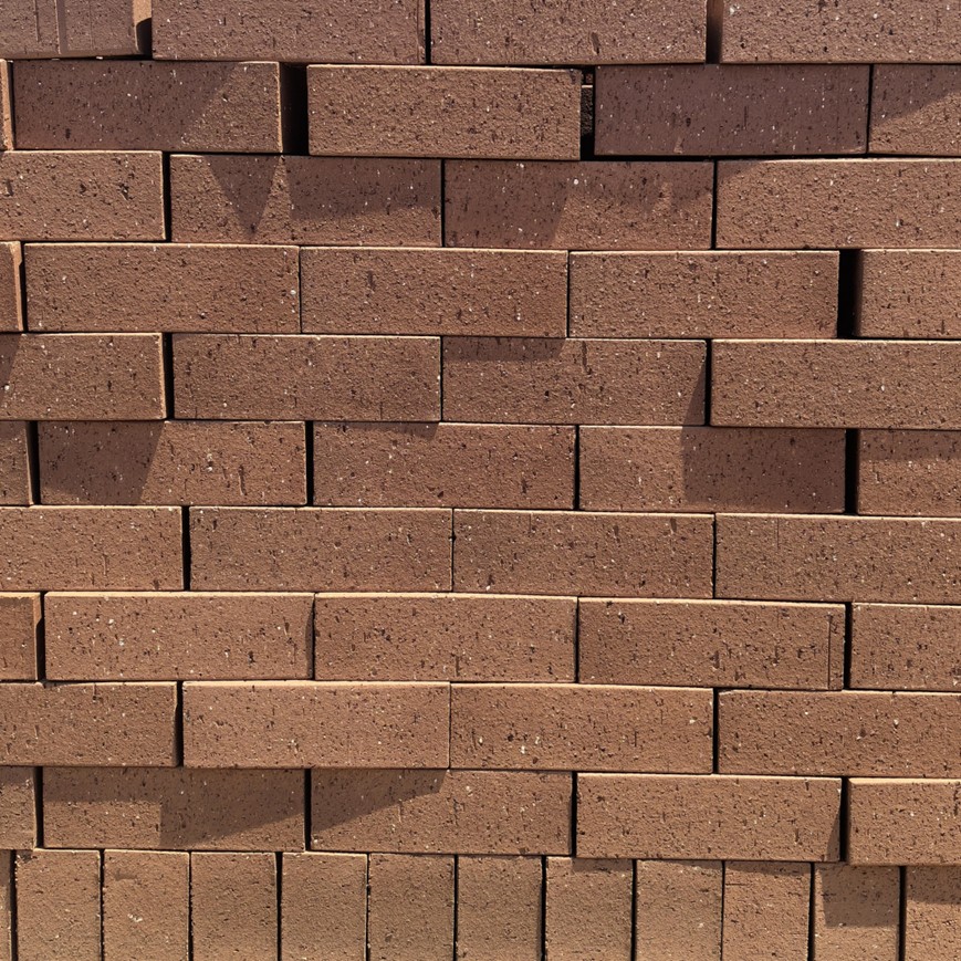 Protea Travertine Face Brick featuring warm pink tones and a rugged pitted stone-like texture for elegant masonry.