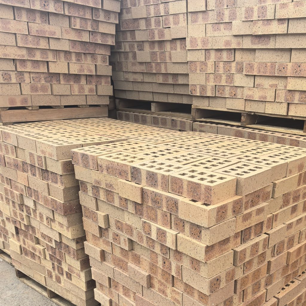 CoroJem Manor Travertine Face Brick featuring an orange clay tone with light red burns, an enlarged profile for efficient construction, and a rugged travertine texture.