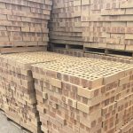 CoroJem Manor Travertine Face Brick featuring an orange clay tone with light red burns, an enlarged profile for efficient construction, and a rugged travertine texture.