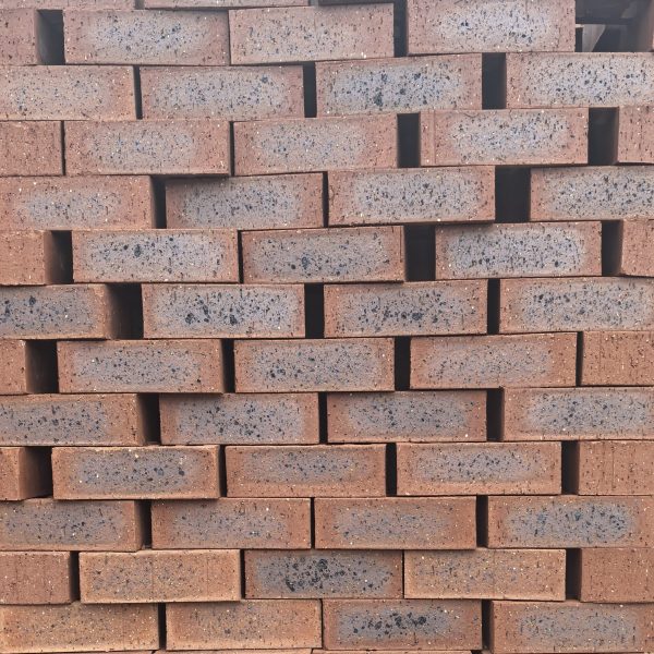 Country Classic Travertine Face Brick featuring rich ruby red colors with a deep blue-burnt flash, a rugged travertine finish, and weather-resistant rough edges.