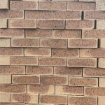 Country Manor Travertine Face Brick featuring a classic yellow clay tone with an orange burn and a rugged travertine finish for premium residential and commercial property walls.