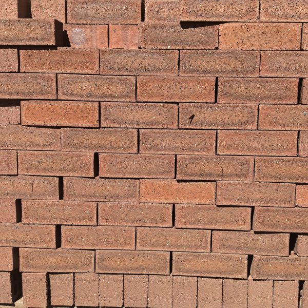 Blackwood Travertine Face Brick featuring a deep red clay color profile with mixed rugged tones, a travertine finish, and a consistent shape for budget-friendly building.