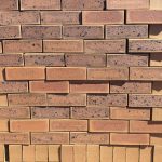 Nala Satin Dark Face Brick featuring a vibrant yellow clay base with a striking dark blue-burnt flash and a smooth satin texture for contemporary architectural designs.