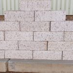 Outdoor pyramid stack of Artisanal Vanilla face bricks displaying heavily grooved rustic texture, pale cream-white color, and dark iron spots.