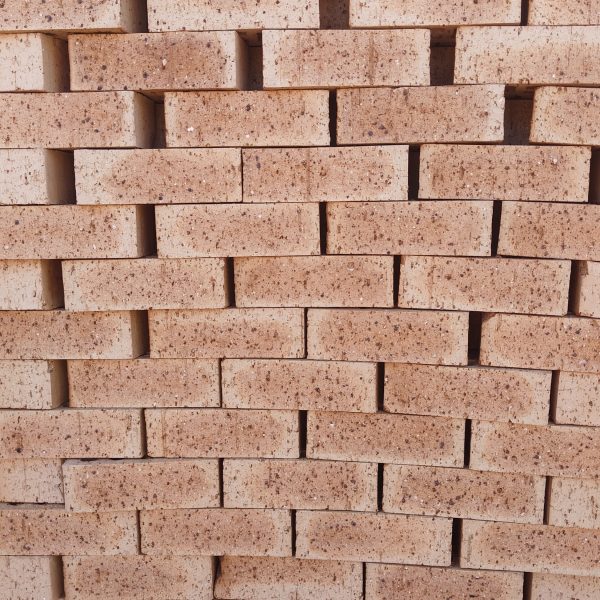 Close-up wall view of stacked Autumn Wheat Travertine face bricks showing light golden-wheat face tones, pitted travertine texture, and dark iron spots.