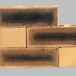 Stacked sample of Granite Satin Face Bricks, a premium, speckled light brown clay face brick with dark hearting and smooth texture, for sale in Gauteng.