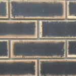 Close-up of Granite Satin Face Bricks laid in a wall section with grey mortar, showing dark center flashes with light tan borders.