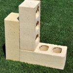 Three Ivory Satin clay face bricks arranged on grass displaying light cream color, smooth satin texture, and core perforations.