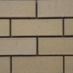 Close-up of Ivory Satin face bricks laid in a wall section with dark mortar joints showing fine speckled texture and uniform cream tone.