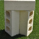 Three Ivory Satin clay face bricks stacked outdoors on grass showing internal core hole perforations and smooth cream finish.