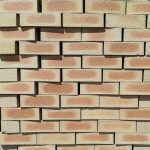 Front-on view of stacked Letaba Satin variation face bricks showing pale cream-yellow margins, smooth satin finish, and distinct soft peach-apricot flashed central cores.