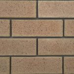 Close-up of Marble Travertine face bricks laid in a wall panel with grey mortar joints showing pitted travertine texture and warm beige-pink tones.