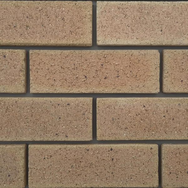 Close-up of Marble Travertine face bricks laid in a wall panel with grey mortar joints showing pitted travertine texture and warm beige-pink tones.