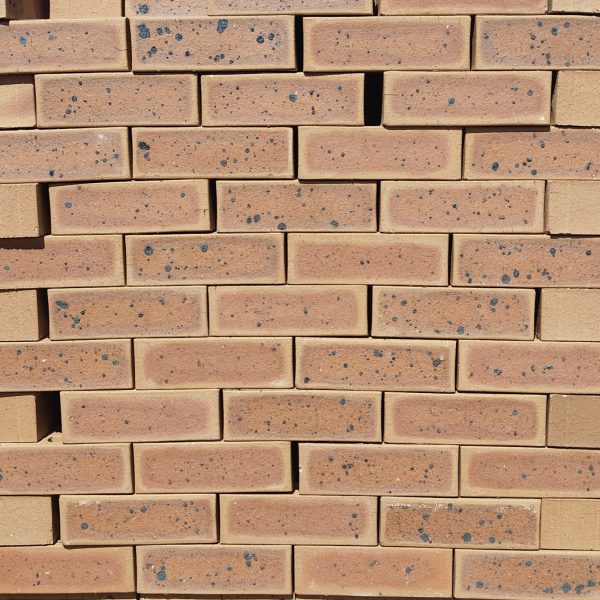 Front-on view of stacked Nala Satin Dark face bricks showing a smooth satin finish, warm golden-tan clay body, reddish-brown heat-flashed centers, and pronounced dark iron spots.