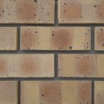 Close-up of Nkwe Satin face bricks laid in a wall panel with grey mortar joints showing smooth satin texture, warm terracotta-buff tones, and dark manganese spots.
