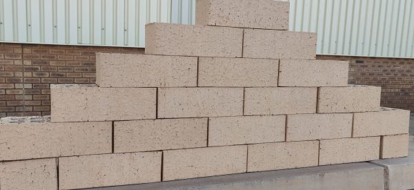 Outdoor pyramid stack of Pampas Satin face bricks displaying smooth satin surface finish, light wheat-tan clay body, and subtle iron speckling.