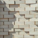 Front-on view of stacked Pampas Satin face bricks showing smooth satin surface finish, ultra-light cream-buff clay body, and subtle fine iron speckling under bright direct sunlight.