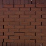 Front-on view of stacked Redwood Travertine Light face bricks showing pitted travertine surface texture, warm terracotta-red clay body, and distinct light orange-apricot flashed center cores.