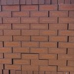 Front-on view of stacked Redwood Travertine Light face bricks showing pitted travertine surface texture, warm terracotta-red clay body, and distinct light orange-apricot flashed center cores.