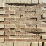 Front-on view of stacked Sapphire Satin Light face bricks showing smooth satin finish, light cream-buff clay body, subtle golden-brown heat flashing, and distinct dark iron spots.