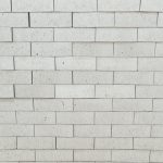 Front-on view of stacked Silver Grey Satin face bricks showing smooth satin finish, crisp light silver-grey clay body, and delicate dark iron speckling under diffuse light.