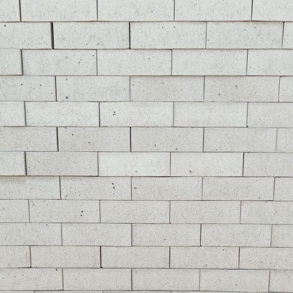 Front-on view of stacked Silver Grey Satin face bricks showing smooth satin finish, crisp light silver-grey clay body, and delicate dark iron speckling under diffuse light.